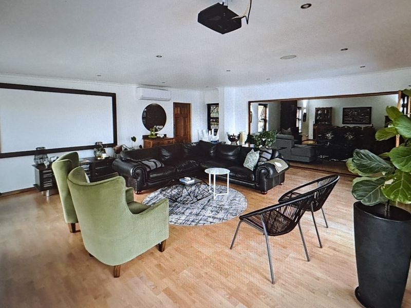 Spacious living room featuring hardwood flooring, recessed lighting, a wall-mounted projection screen, and a split-system air conditioning unit.