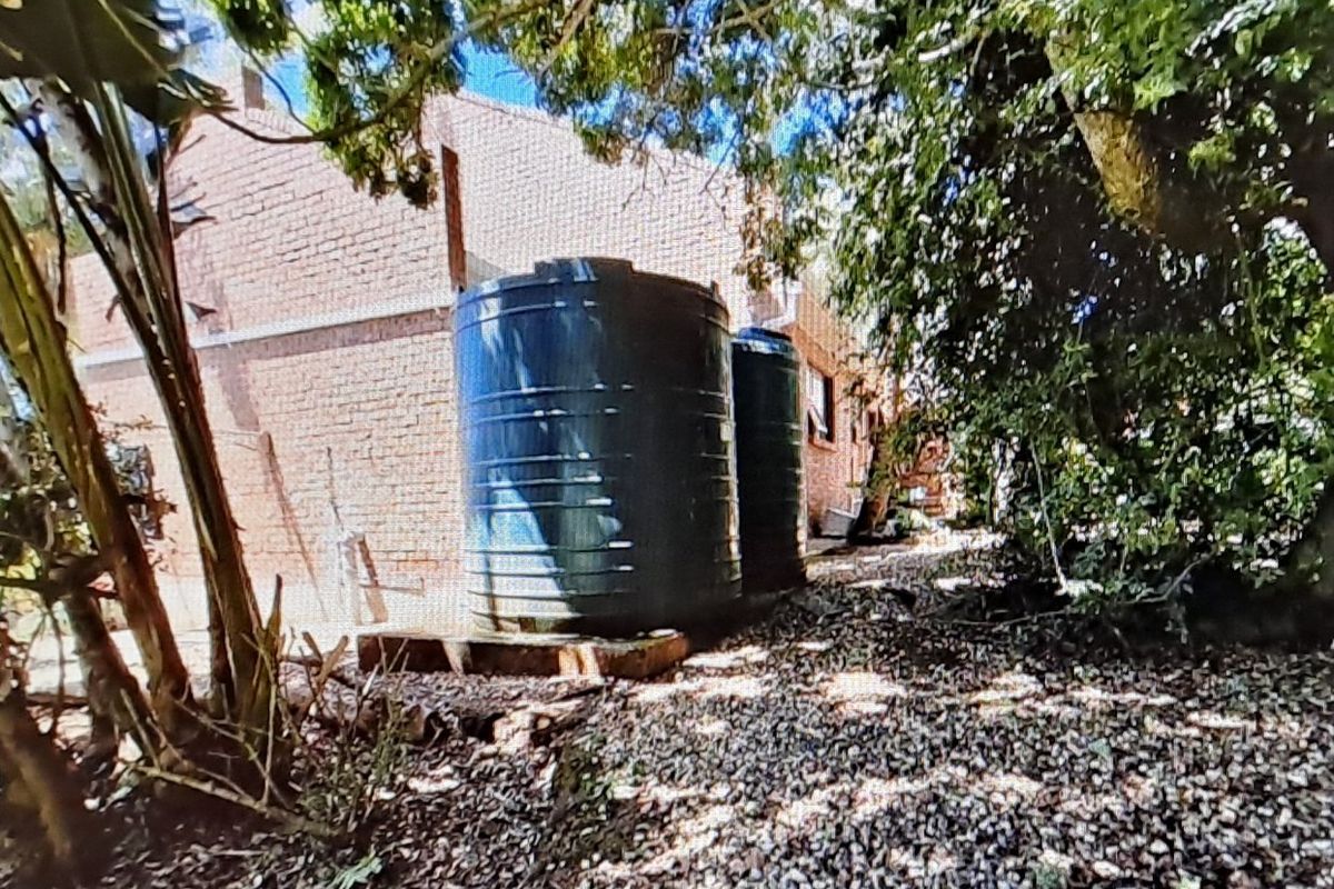 Rear exterior view of the property featuring two large water storage tanks positioned against the brick building facade.