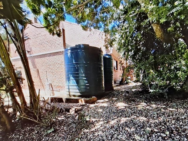 Rear exterior view of the property featuring two large water storage tanks positioned against the brick building facade.