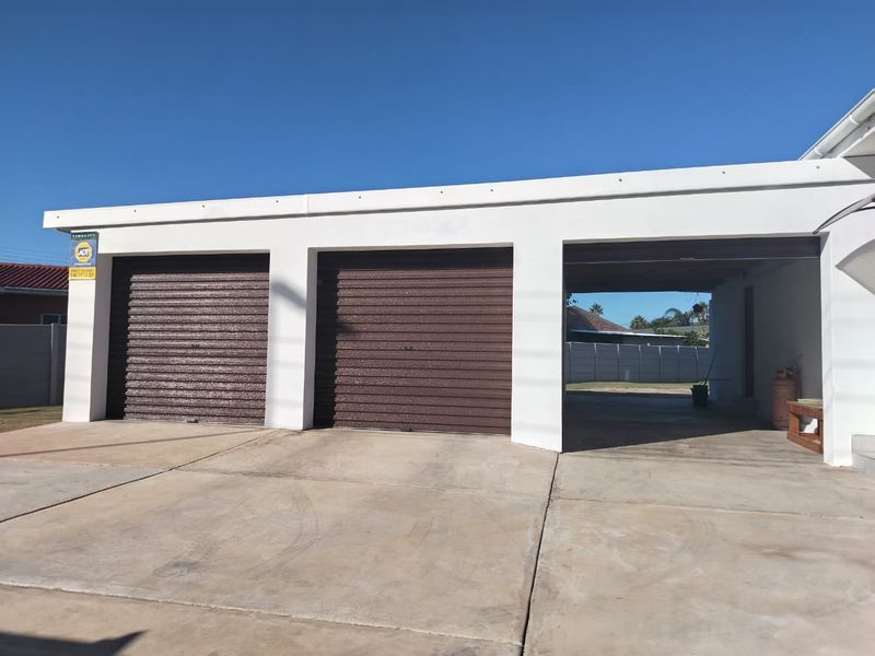 A multi-car garage featuring two secure roller doors and an additional open-sided carport bay, set on a concrete driveway.