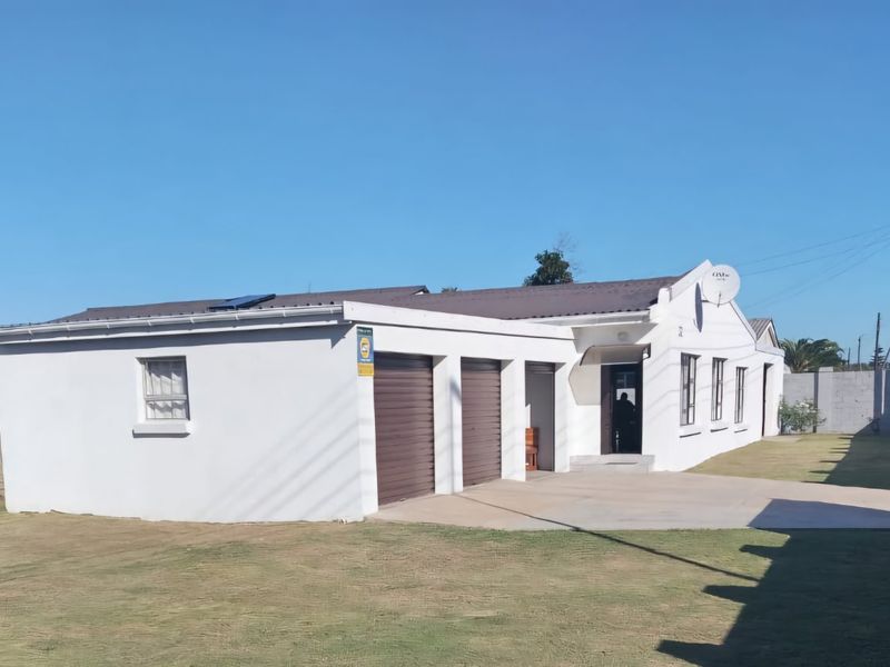 Front view of a single-story house featuring a triple garage, concrete driveway, and secure perimeter walling on a spacious lawn.