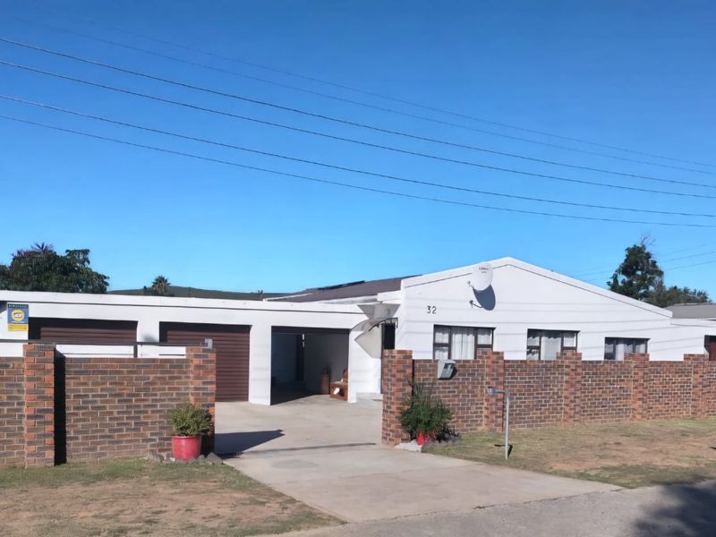 Front elevation of a single-story house featuring a brick boundary wall, concrete driveway, and double garage access.