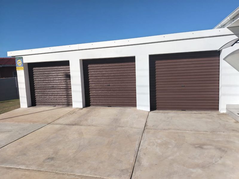 A triple garage featuring brown roller doors and a concrete driveway, providing secure parking space for three vehicles.
