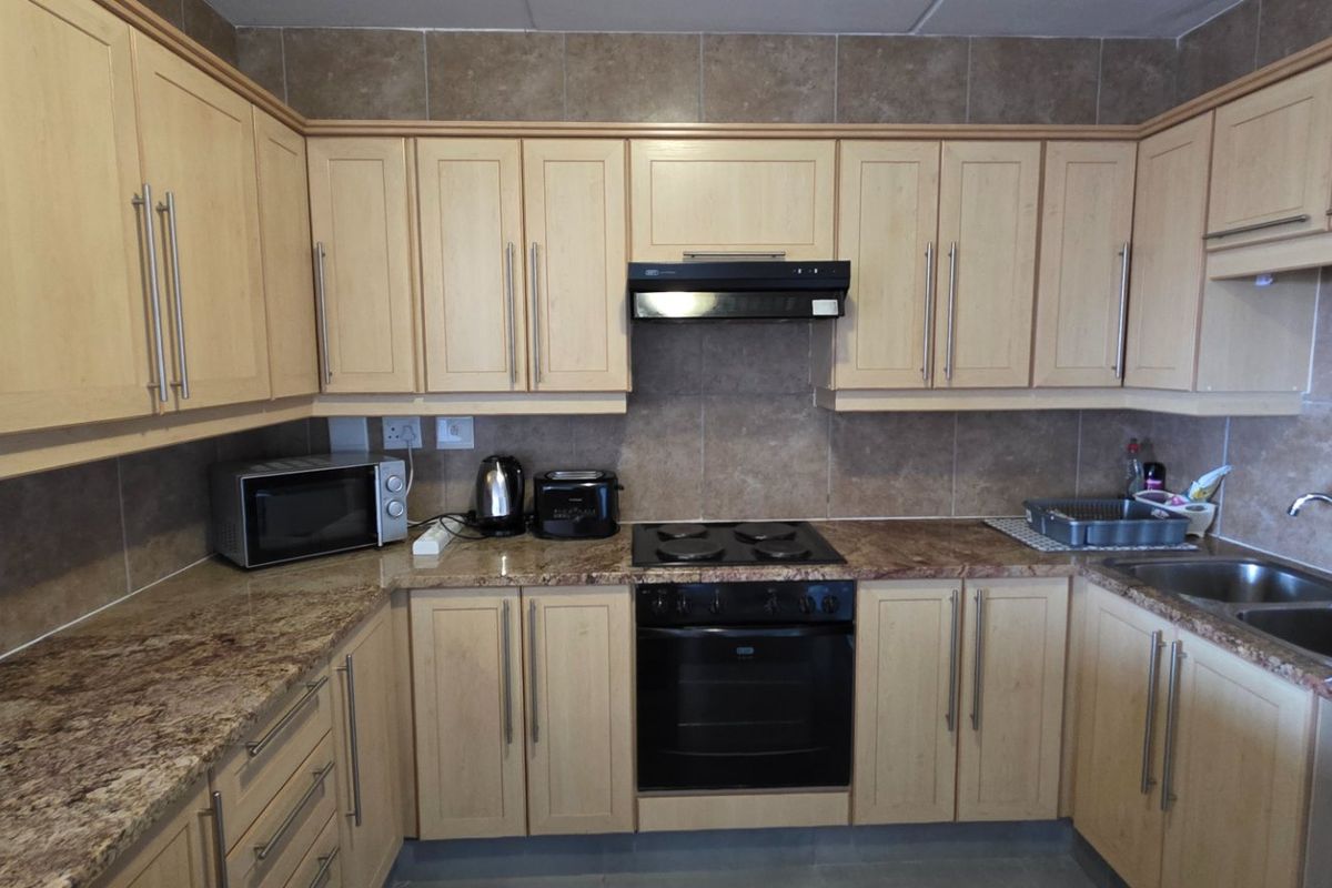 Functional kitchen featuring light wood cabinetry, granite countertops, tiled backsplash, and integrated appliances including an oven, hob, and extractor fan.