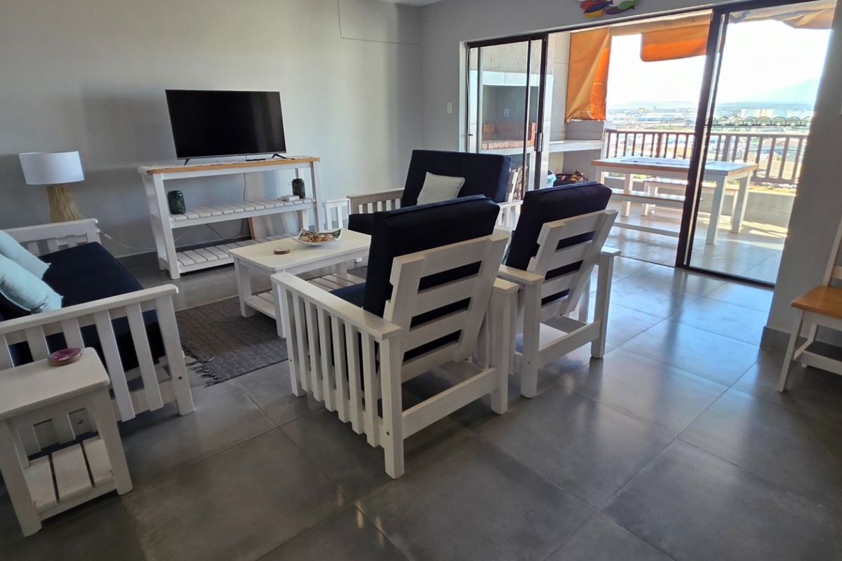 A living room featuring large format floor tiles and a sliding glass door providing access to an outdoor balcony area.