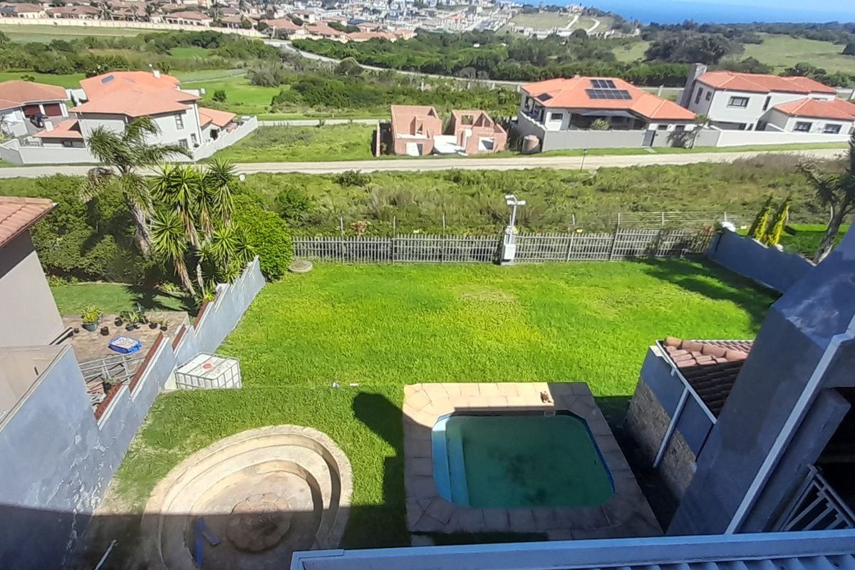 Aerial view of a residential backyard featuring a swimming pool, sunken fire pit, and lawn area with surrounding estate views.