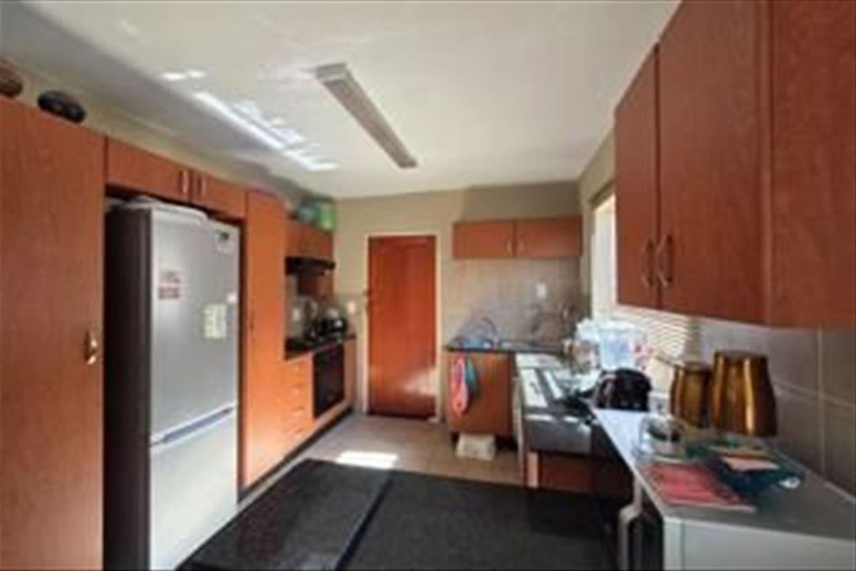 A functional kitchen featuring wood-tone cabinetry, laminate countertops, and integrated cooking appliances, offering a practical layout for daily meal preparation.