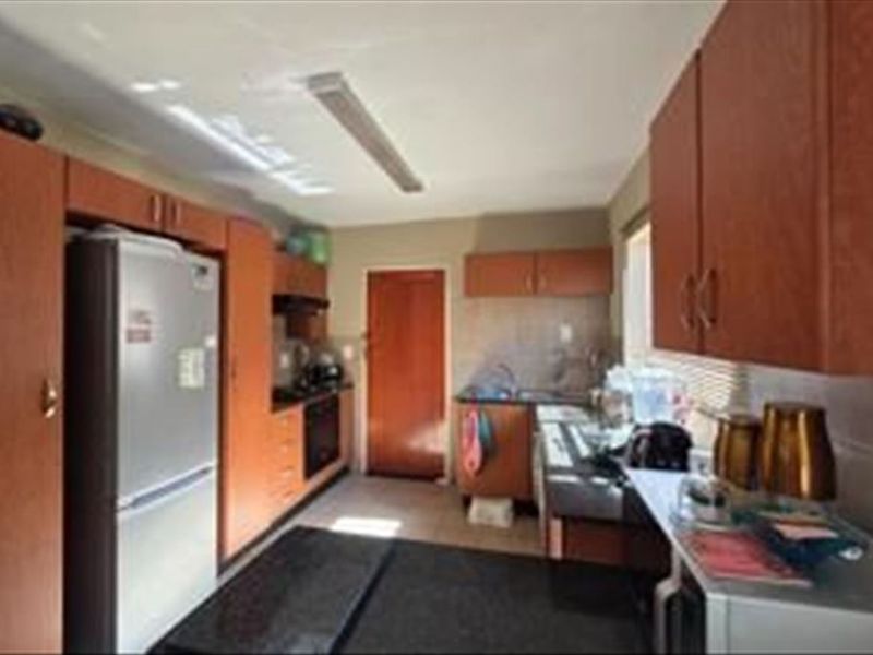 A functional kitchen featuring wood-tone cabinetry, laminate countertops, and integrated cooking appliances, offering a practical layout for daily meal preparation.