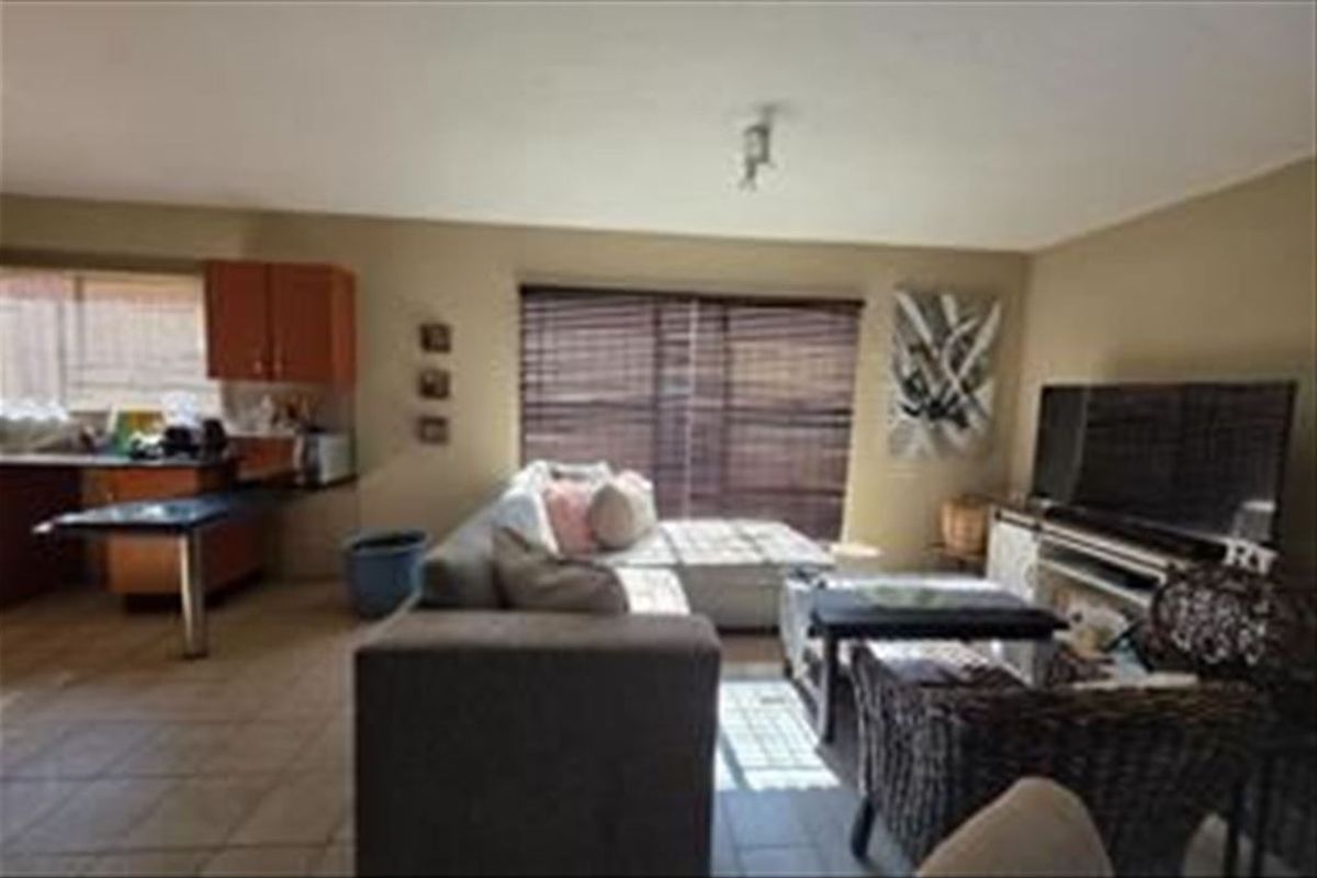 Open-plan living area featuring tiled flooring and an integrated kitchen space with cabinetry and countertops.