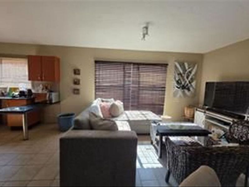 Open-plan living area featuring tiled flooring and an integrated kitchen space with cabinetry and countertops.