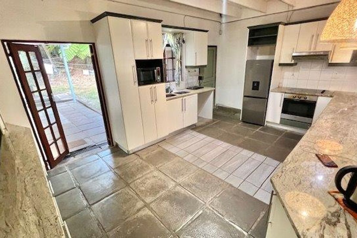 A functional kitchen featuring granite countertops, built-in appliances, and direct access to an outdoor patio area through a glass-paneled door.