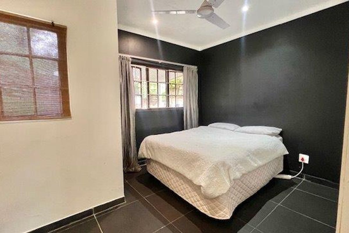 A bedroom featuring dark accent walls, tiled flooring, a ceiling fan, and windows with fitted blinds and curtains.