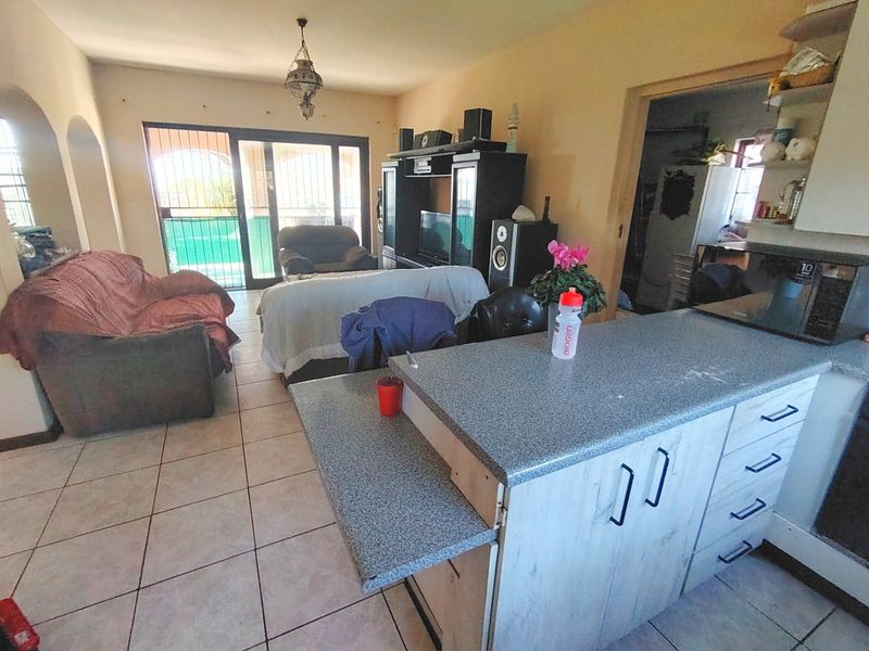 Open plan living area featuring a kitchen island with laminate cabinetry, tiled flooring, and sliding glass doors leading to an outdoor space.