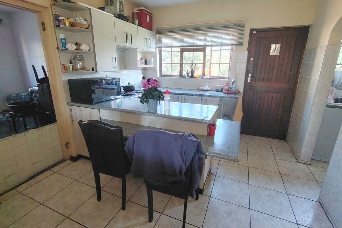 A functional kitchen featuring built-in cabinetry, laminate countertops, tiled flooring, and a timber door leading to the exterior.