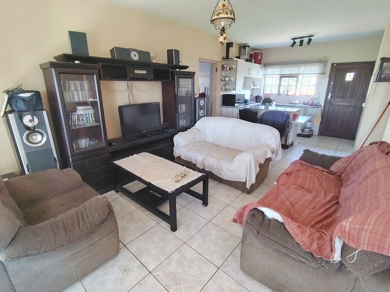 Open-plan living and kitchen area featuring tiled flooring, kitchen cabinetry with an island, and direct access to an external door.