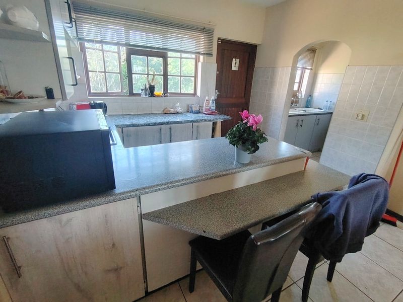 Functional kitchen featuring granite countertops, a breakfast bar, tiled backsplash, and a separate scullery area with additional cabinetry.