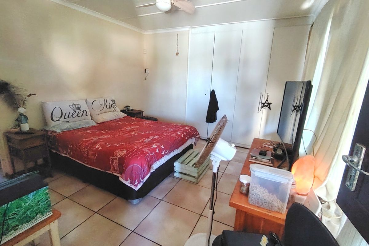 A functional bedroom featuring tiled flooring, built-in cupboards for storage, and a ceiling fan for climate control.