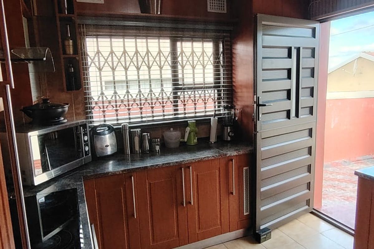 A functional kitchen featuring wood-finish cabinetry, granite countertops, and direct access to an outdoor area through a secure door.