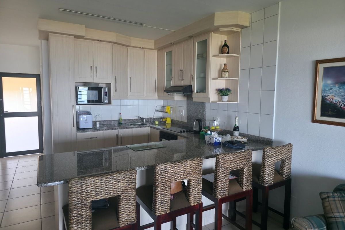 A functional kitchen featuring light wood cabinetry, granite countertops, a breakfast bar, and a tiled backsplash, providing a practical layout for daily use.
