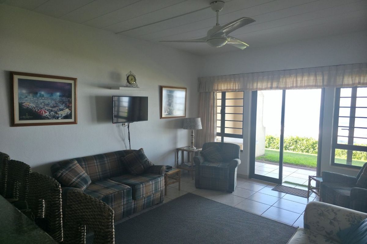 A living room featuring tiled flooring, a ceiling fan, and large sliding glass doors providing access to an outdoor patio area.