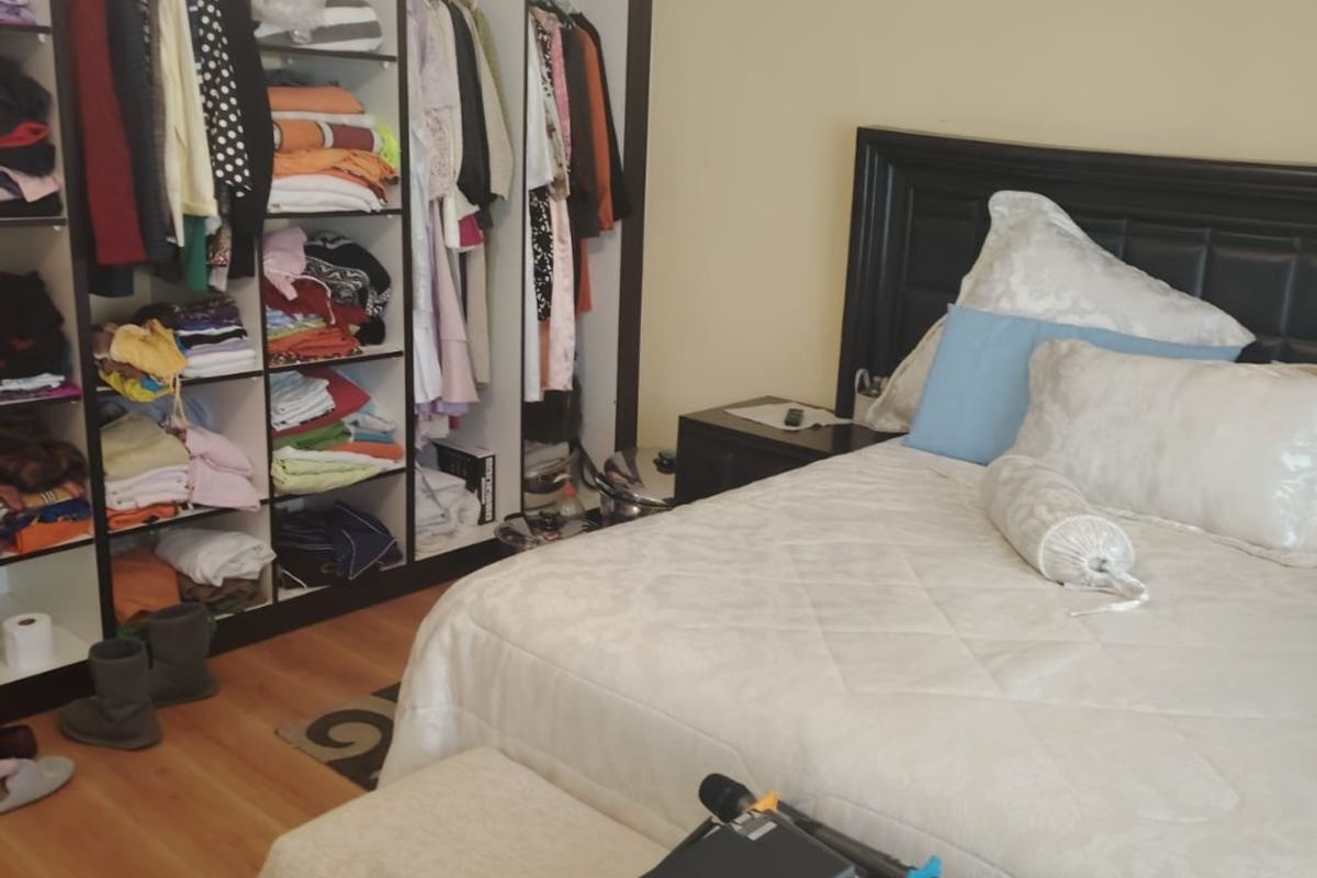 A bedroom featuring laminate flooring, crown molding, and a large built-in wardrobe with open shelving and hanging space.