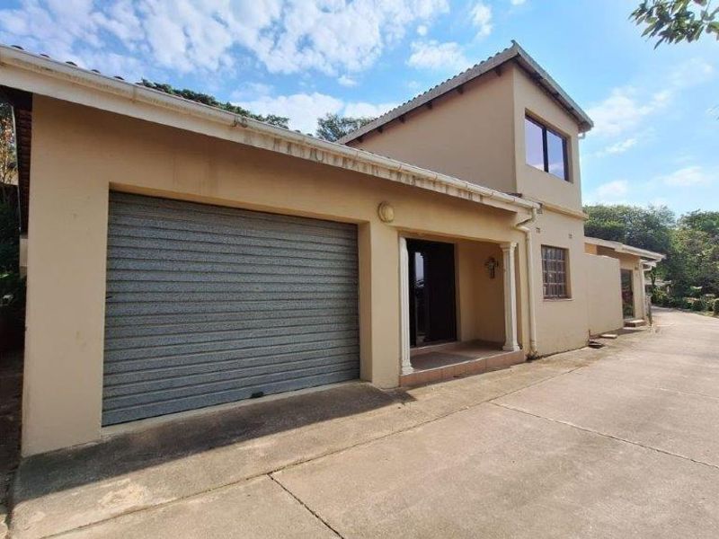 Front exterior view of a townhouse featuring a roller garage door, covered entrance, and concrete driveway access.