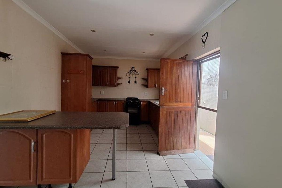 A functional kitchen featuring wooden cabinetry, tiled flooring, and a breakfast nook, with direct access to an outdoor area.