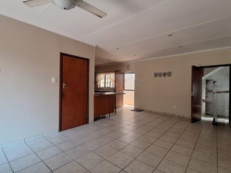 Open plan living area featuring tiled flooring, ceiling fan, and direct access to the kitchen space.
