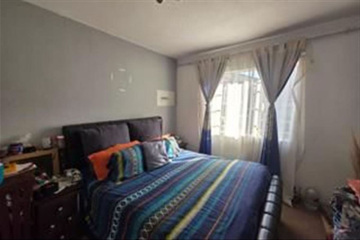 A standard bedroom featuring a window with curtain rails and neutral wall finishes.