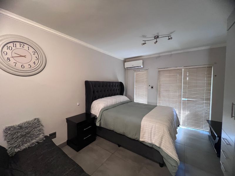 A well-maintained bedroom featuring tiled flooring, an air conditioning unit, and venetian blinds, providing a comfortable and functional living space.
