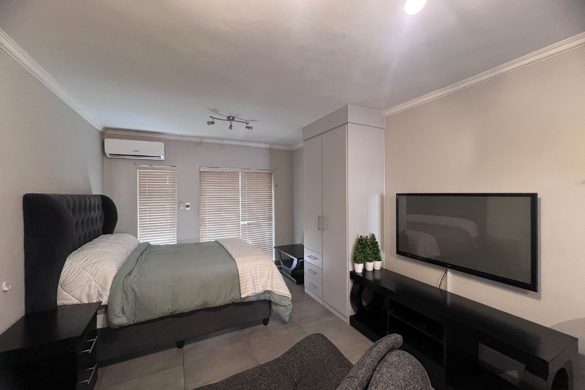 A well-maintained bedroom featuring tiled flooring, a built-in wardrobe, and a wall-mounted air conditioning unit with venetian blinds for privacy.