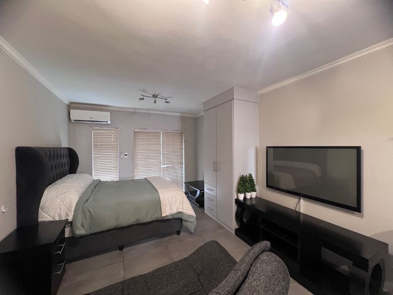 A well-maintained bedroom featuring tiled flooring, a built-in wardrobe, and a wall-mounted air conditioning unit with venetian blinds for privacy.