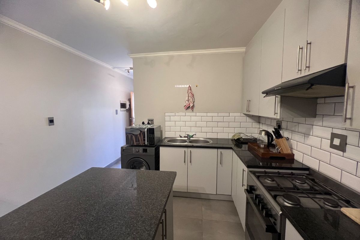 Modern kitchen featuring granite countertops, subway tile backsplash, gas stove with extractor fan, and ample built-in cabinetry.