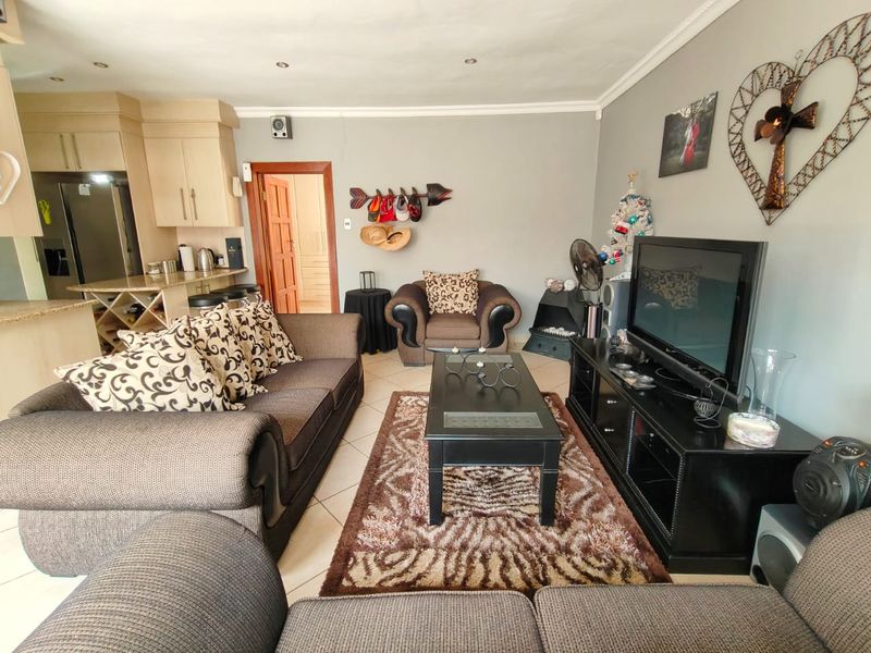 Open-plan living area featuring tiled flooring, recessed lighting, and an integrated kitchen with granite countertops, creating a functional and connected living space.