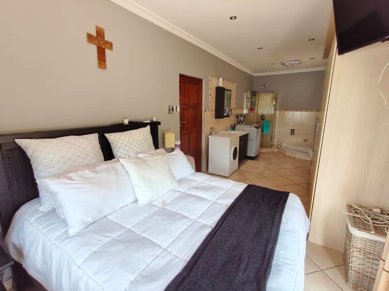 Spacious bedroom featuring an integrated en-suite bathroom with a shower, tiled flooring, and built-in cabinetry, offering a functional and open layout.