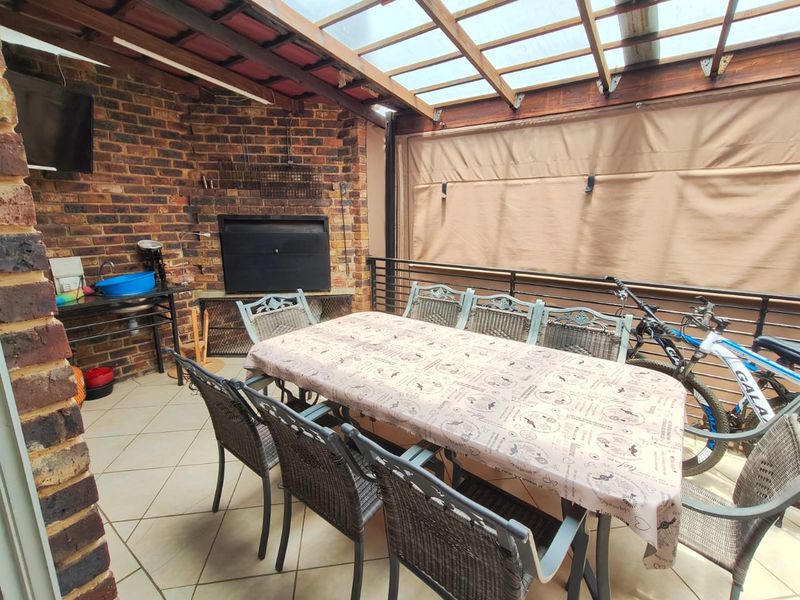 Covered patio area featuring a built-in braai, tiled flooring, and an exposed timber roof structure, ideal for outdoor entertaining.
