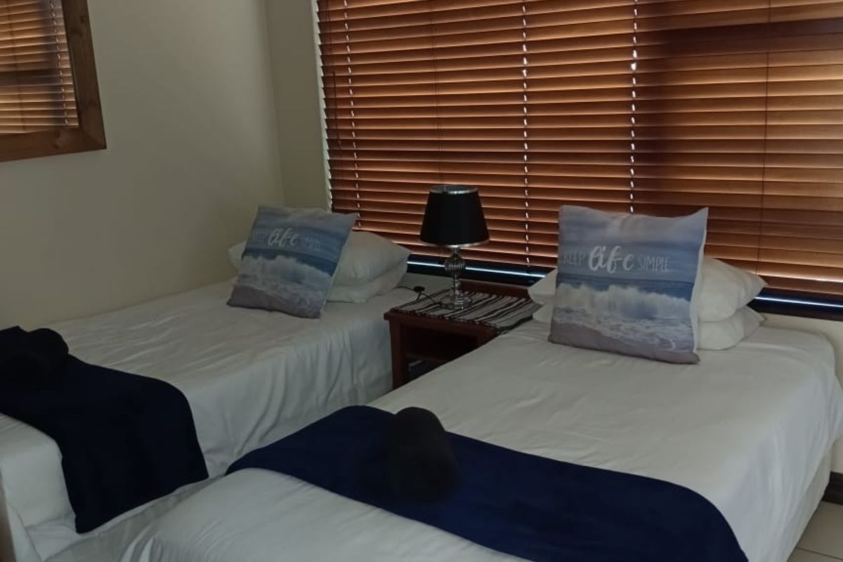 A bedroom featuring tiled flooring and wooden venetian blinds, providing a functional space with neutral wall finishes.