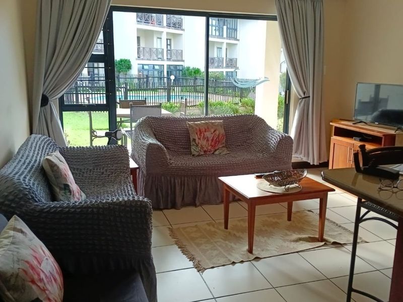 A living room featuring tiled flooring, a ceiling fan, and large sliding glass doors that provide access to an outdoor patio area.