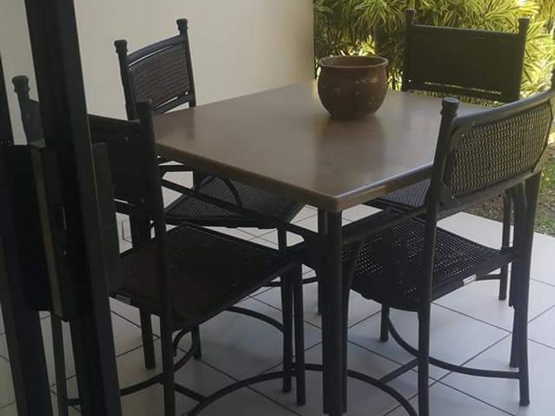 A covered patio area featuring tiled flooring and access via a sliding glass door, overlooking a landscaped garden area.