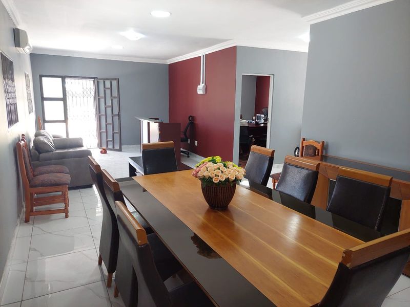 Spacious open-plan commercial area featuring tiled flooring, recessed lighting, and neutral grey and accent walls, suitable for a reception or office meeting space.