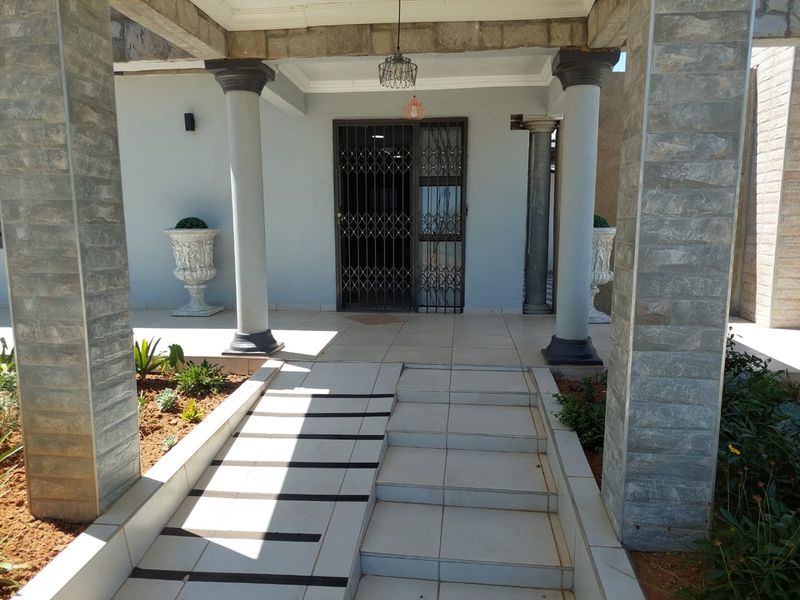 Covered entrance featuring a tiled porch, wheelchair ramp, and stone-clad support columns with a secure metal gate.