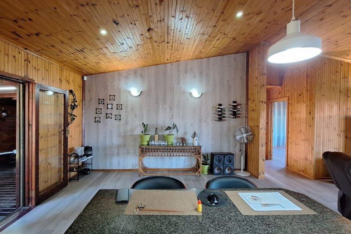 Spacious living area featuring extensive timber-clad walls and ceilings, recessed lighting, and modern laminate flooring, creating a warm and rustic atmosphere.