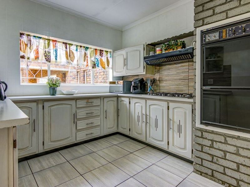 A functional kitchen featuring built-in cabinetry, a gas hob with extractor, and a distinctive brick feature wall with a built-in oven.