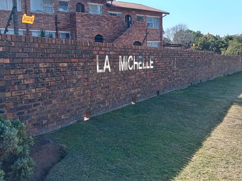 Exterior view of the La Michelle apartment complex featuring a face brick boundary wall and multi-story residential building.