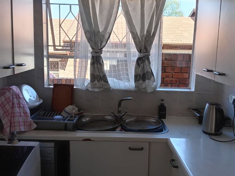 A functional kitchen featuring a double bowl sink, tiled splashback, and built-in cabinetry with a window overlooking the exterior.