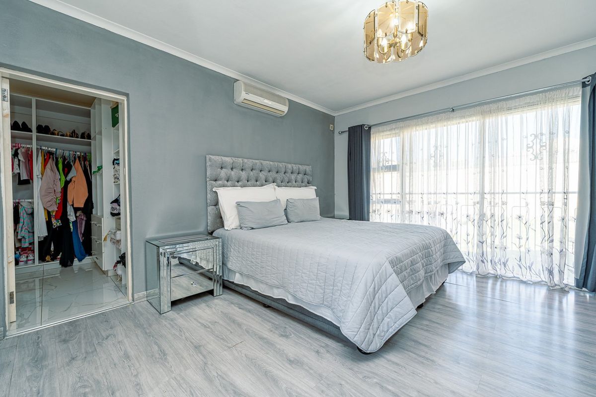 Spacious bedroom featuring light laminate flooring, a built-in wardrobe, split-system air conditioning, and direct access to an outdoor area via sliding glass doors.