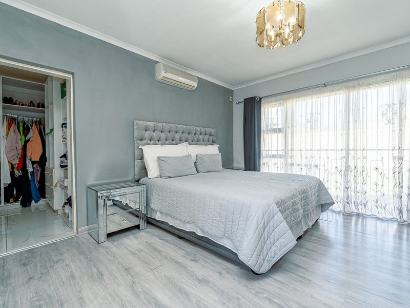 Spacious bedroom featuring light laminate flooring, a built-in wardrobe, split-system air conditioning, and direct access to an outdoor area via sliding glass doors.