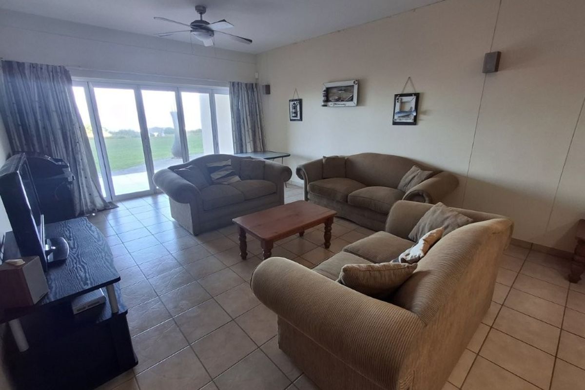 Spacious living room featuring ceramic floor tiles, a ceiling fan, and large sliding glass doors providing natural light and access to the outdoor area.