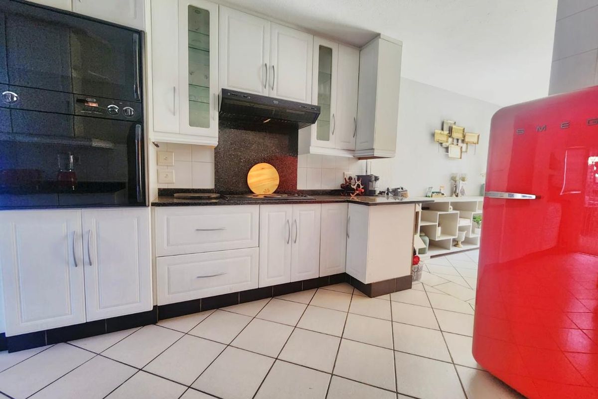 A functional kitchen featuring white cabinetry, granite countertops, a tiled backsplash, and ceramic floor tiles, offering a clean and practical cooking space.