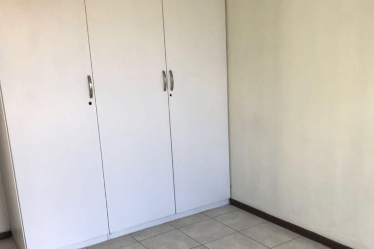 A clean, empty bedroom featuring neutral tiled flooring and white built-in cupboards, providing a blank canvas for personalization.